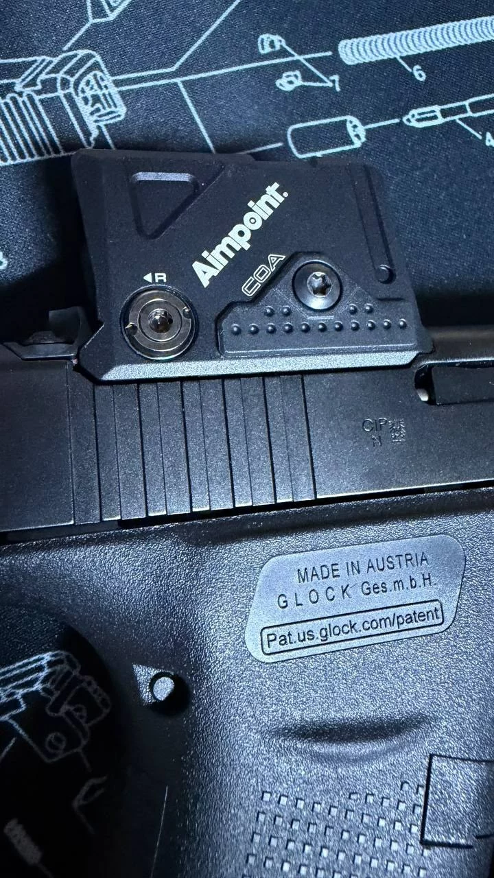 Point rouge Aimpoint COA monté sur la culasse d'un Glock 43X, posé sur un tapis de démontage.