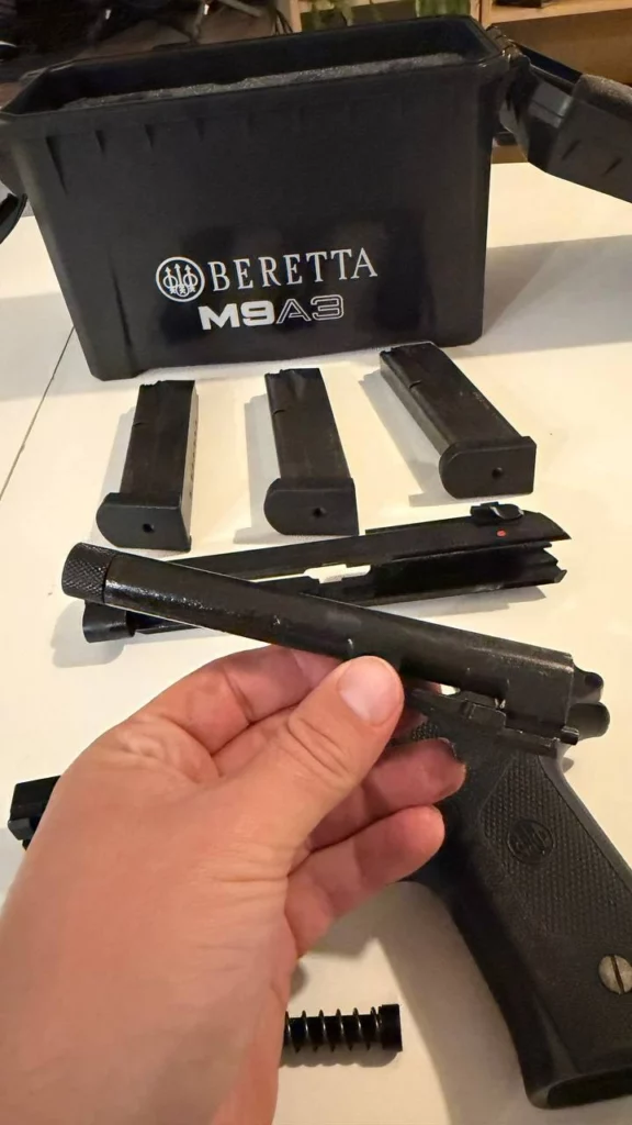 Canon du Beretta M9A3 tenu à la main au-dessus de la carcasse et de la culasse démontées.