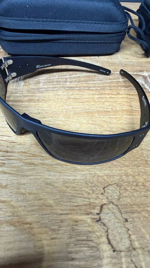 Lunettes Gatorz à verres fumés, branche marquée Z87+ MILSPEC Ballistic, posées sur une table en bois.