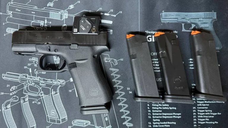Pistolet Glock 43X noir avec point rouge sur la culasse, posé sur un tapis d'entretien à côté de trois chargeurs à élévateur orange.