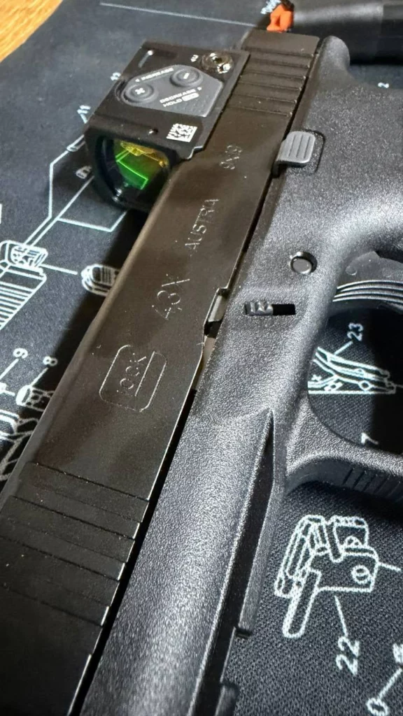 Gros plan sur la culasse du Glock 43X marquée Austria 9x19, avec le point rouge fermé monté à l'arrière.