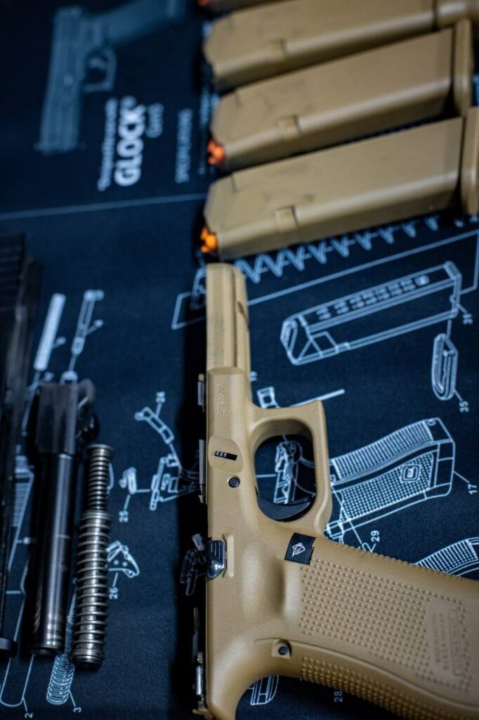 Carcasse du Glock 17 Gen5 à côté du canon et du ressort, chargeurs en arrière-plan