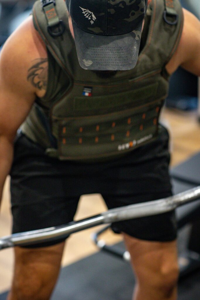 Gilet lesté et barre de musculation en main
